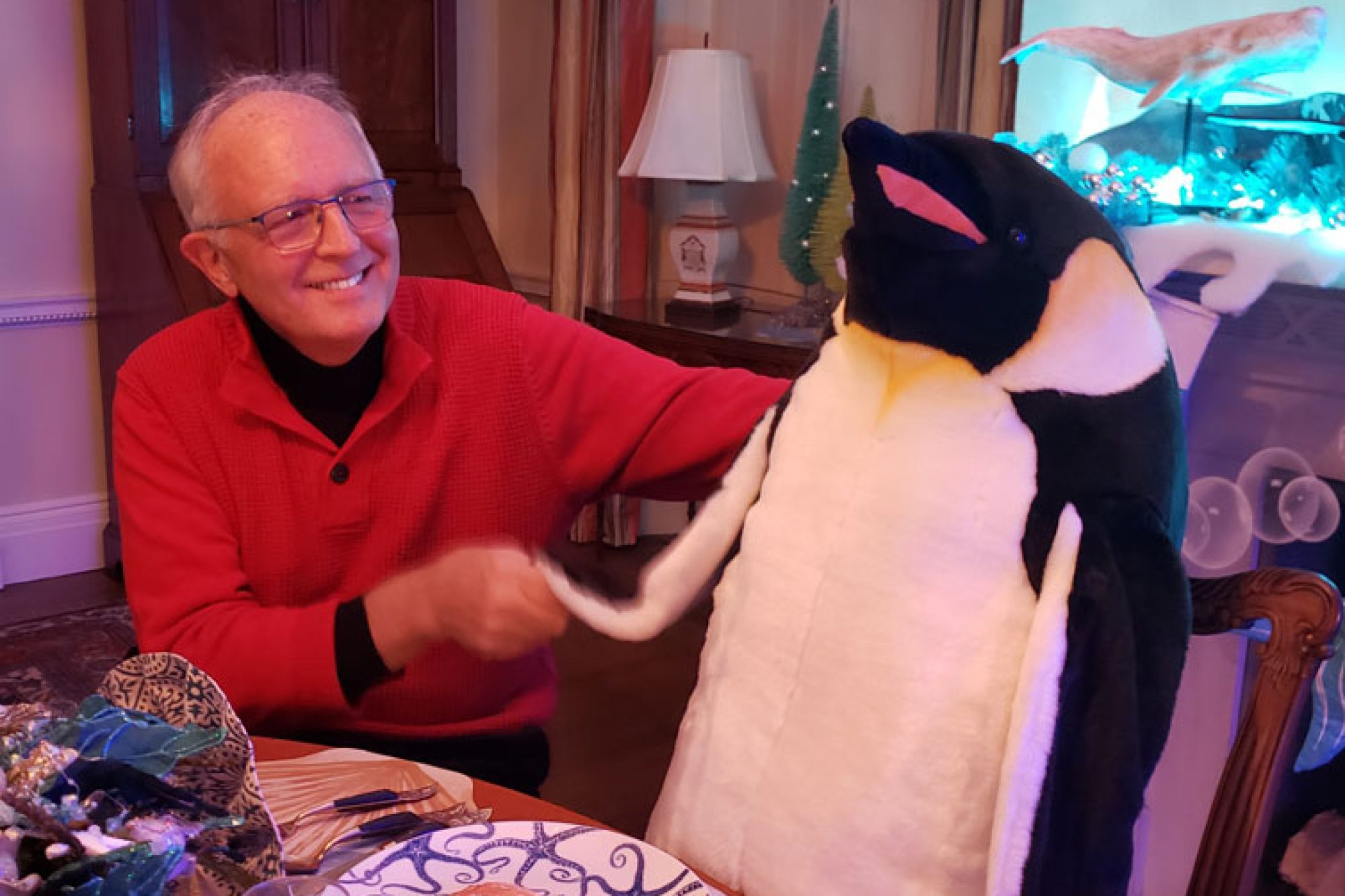 Dick shaking the hand of a giant plush penguin.